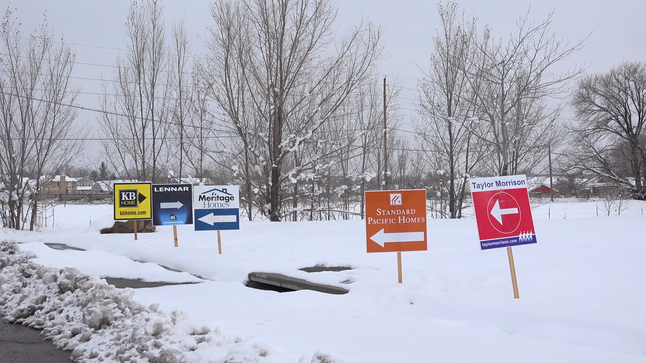 A slightly later view of the snowy Arvada roadside shows KB Home, Lennar, Meritage Homes, Standard Pacific Homes, and Taylor Morrison signs with no visible people.