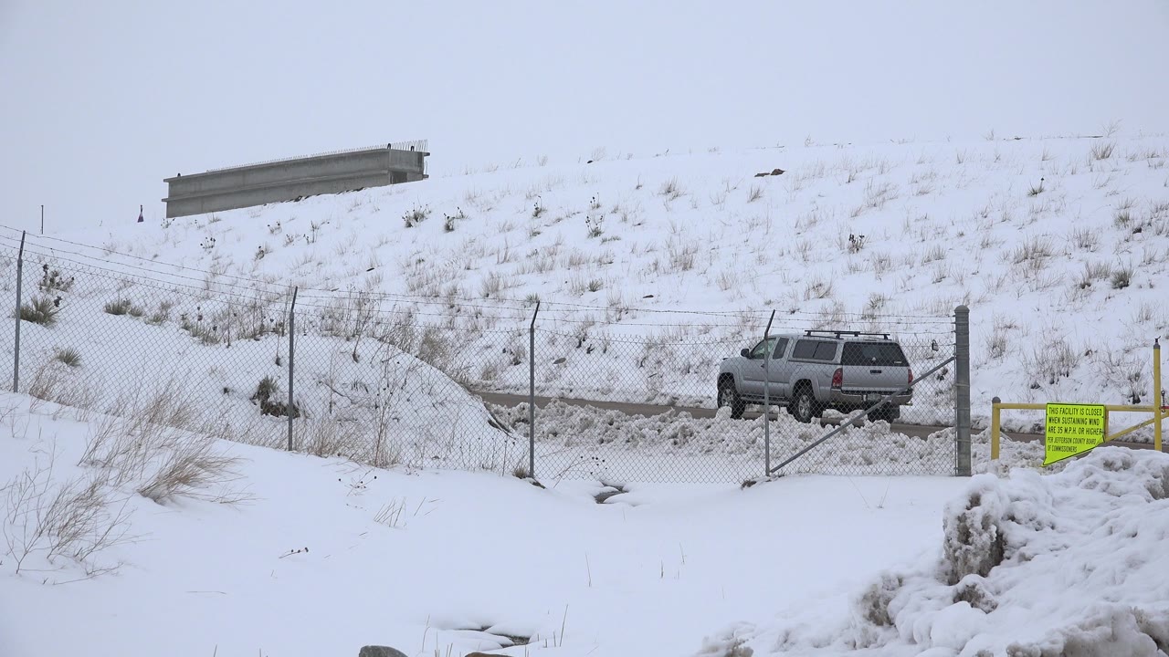 Silver SUV near a snowy fenced road and hillside