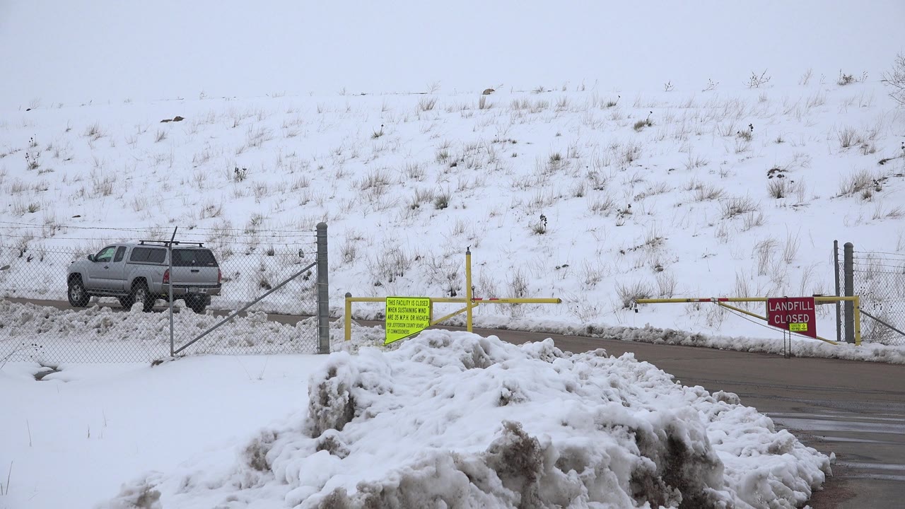 Gray SUV beside a closed snowy road gate
