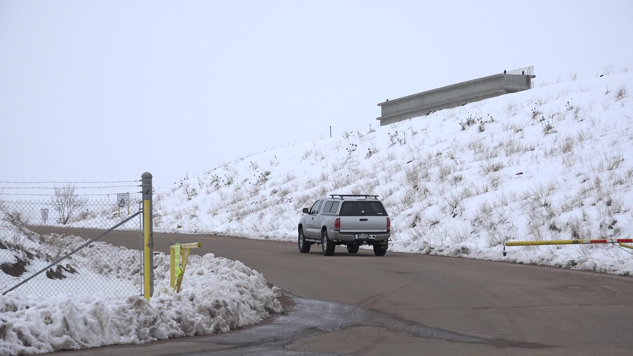Silver SUV near a snow-covered road gate