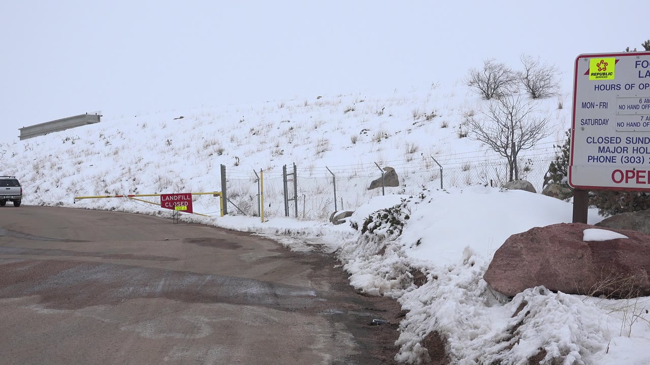 The Arvada, Colorado driveway remains framed with slushy pavement in front, a yellow gate across the road, red closed sign, snowy hill, and no visible people.