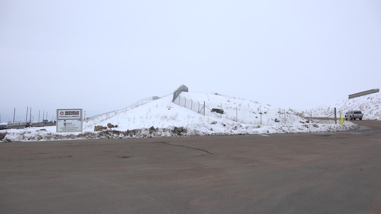Snow-covered roadside lot with business sign and parked vehicle