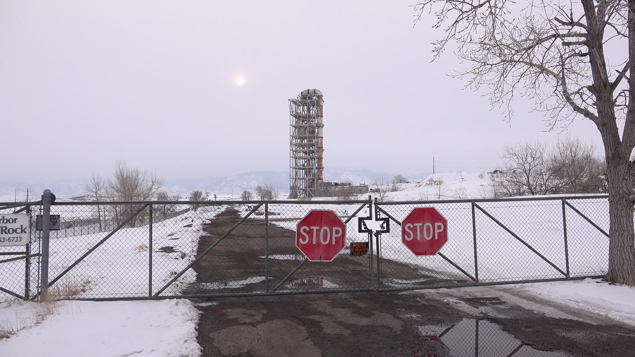 Snowy gated road with stop signs and a distant tower-like structure.