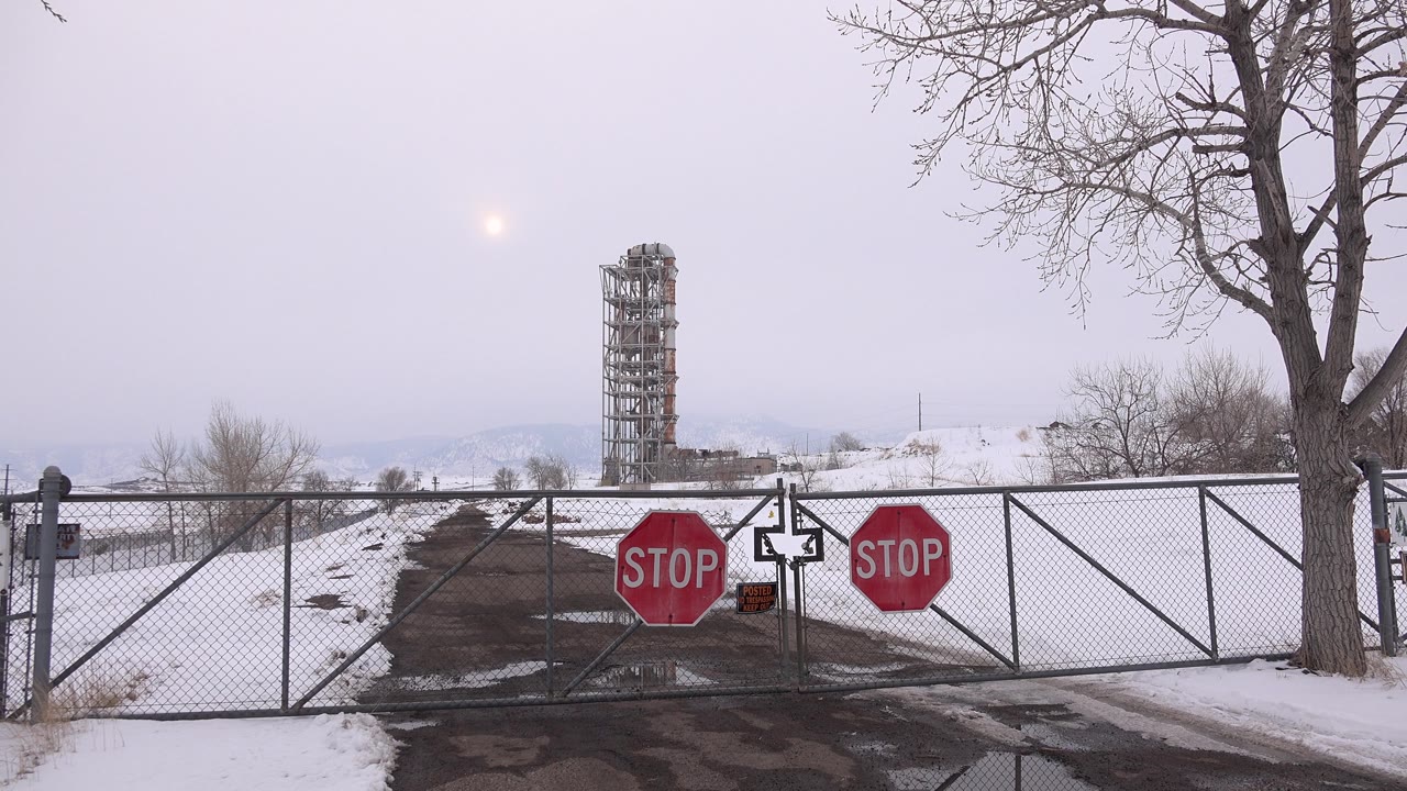 Closed gate across winter road with stop signs and snow fields