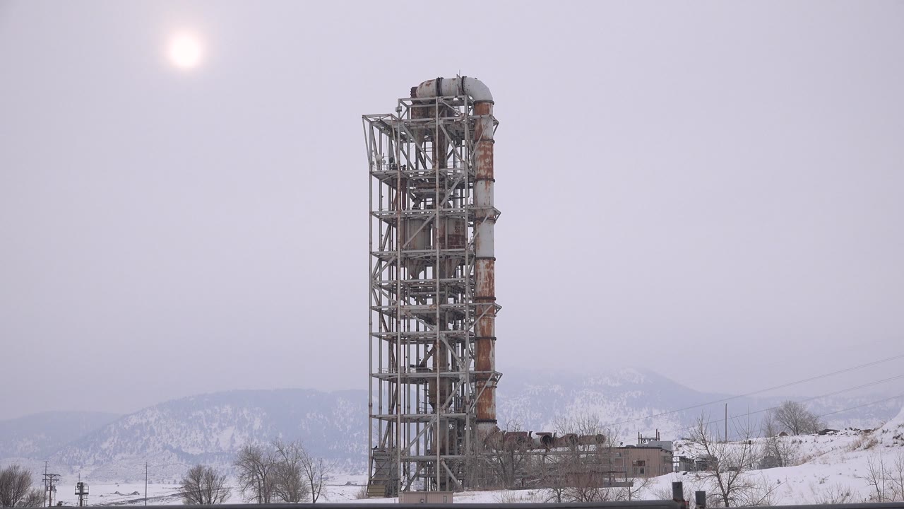 Tall unfinished tower beside snowy hills and bare trees
