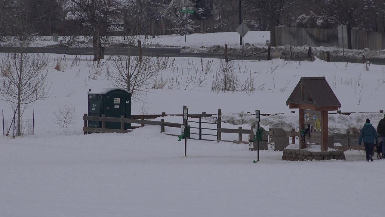 Snowy park scene with kiosk and a person moving toward the right edge.