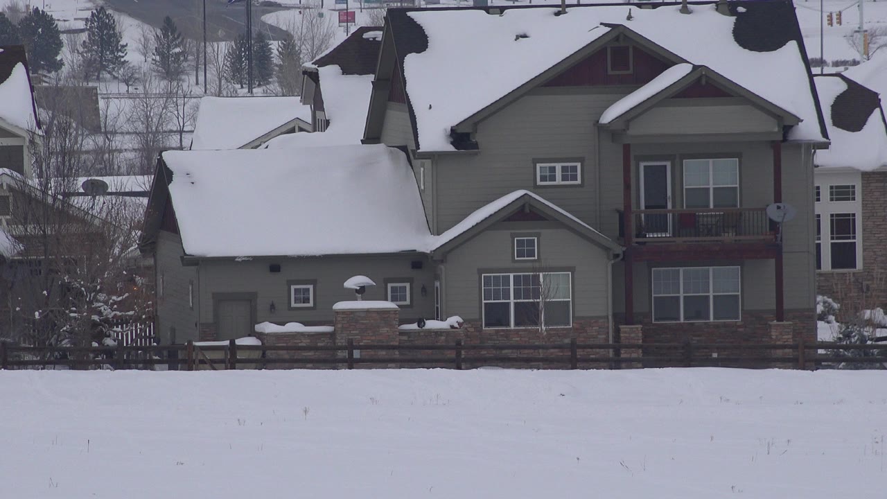 Snow-covered private house in Arvada, Colorado with a wide white field in the foreground and no visible people at the start of the clip.