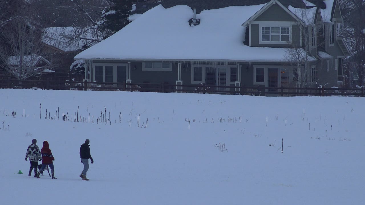 In Arvada, Colorado, the group has moved farther across the white field while the dark house and snowy roof remain fixed in the background.