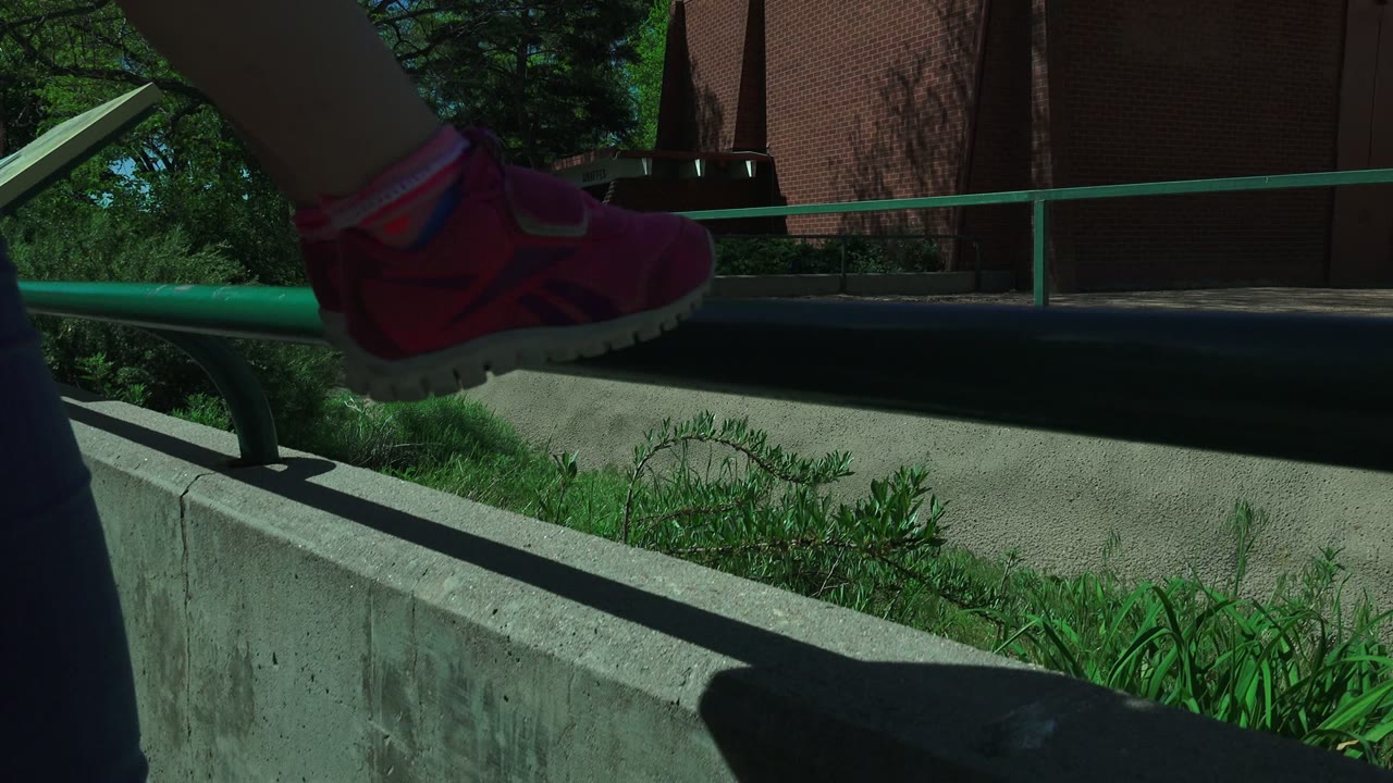 Partial view of a woman holding a child near a concrete wall outdoors.