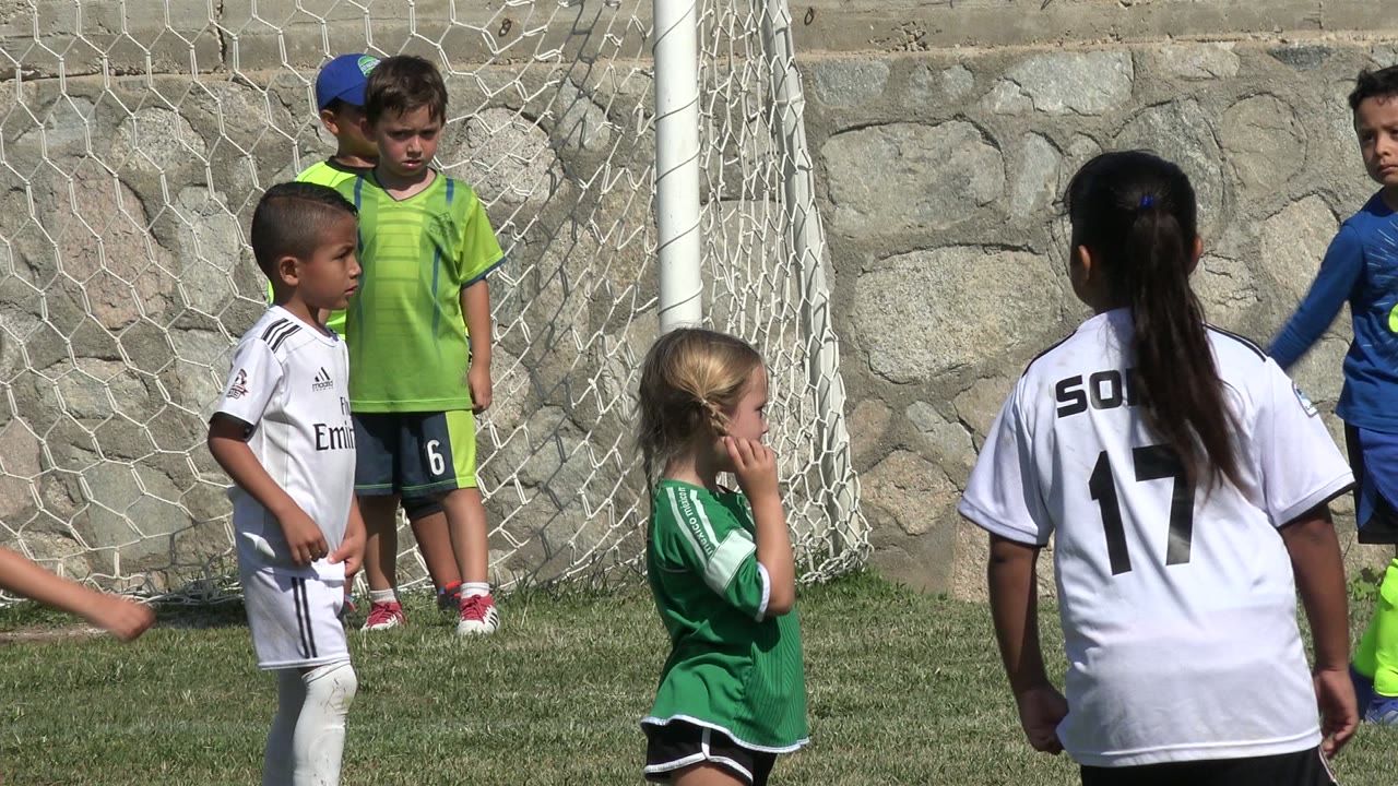 A girl in a white number 17 jersey faces other children in soccer uniforms near the goal net in San Jose Del Cabo, Mexico.