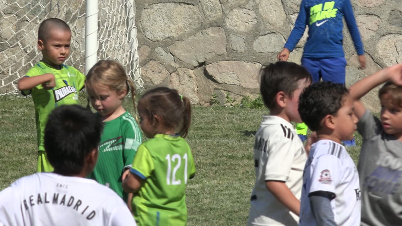 A boy in a green uniform stands near other children in white and green soccer clothes in San Jose Del Cabo, Mexico, with the goal net behind them.