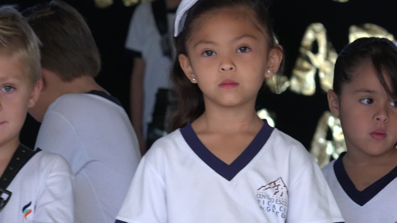 Close view of children in white uniforms waiting in line.