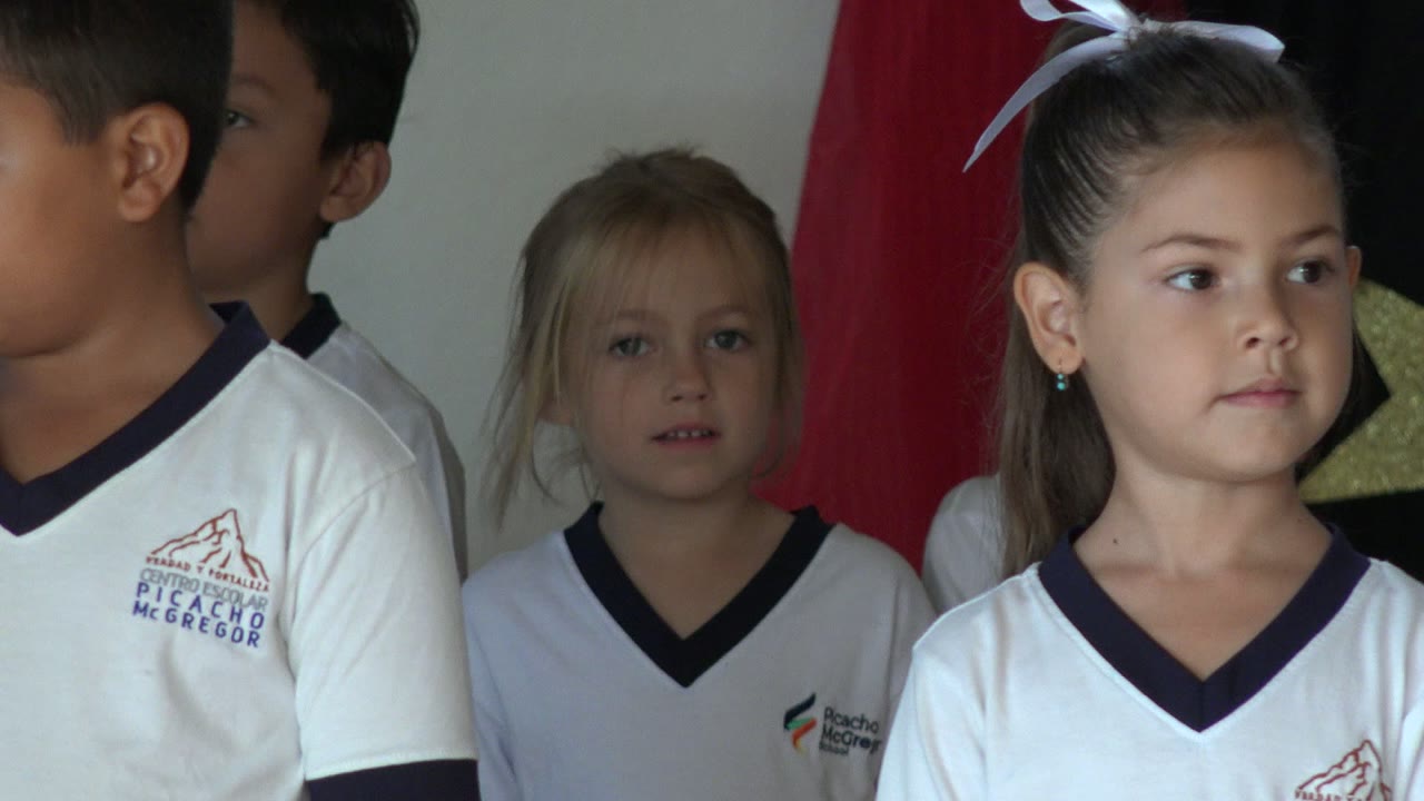 In San Jose del Cabo, Mexico, children in white shirts remain indoors while a blurred white-clad figure passes through the foreground and partially blocks the center of the frame.