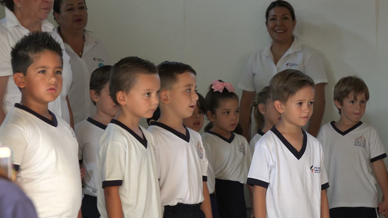 Preschool children in white uniforms standing in rows indoors