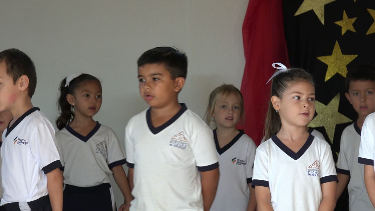 Children in matching school uniforms standing before star decorations.
