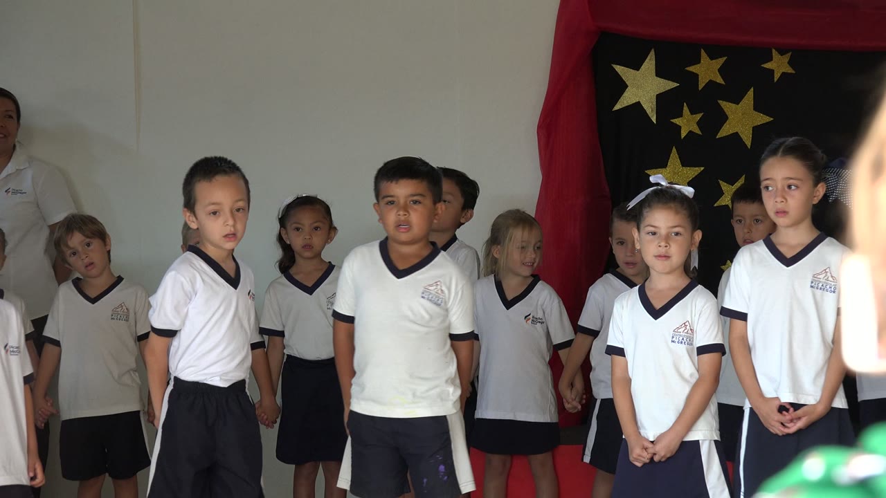 Schoolchildren in uniforms standing in front of a star backdrop.
