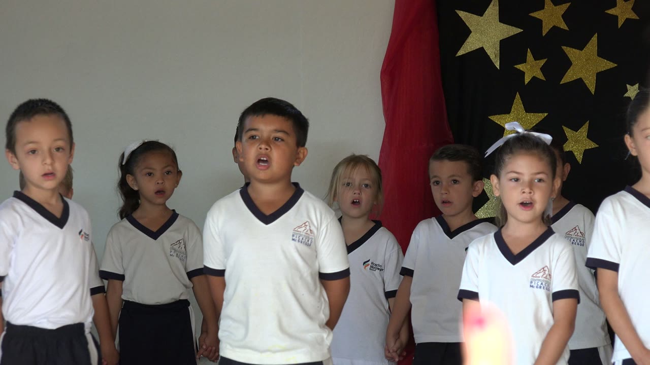 Front row of children singing on a decorated indoor stage.