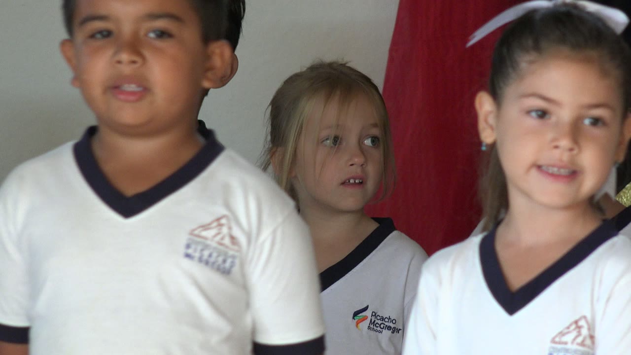 A boy in a white uniform shirt is cropped in the foreground while other children remain visible behind him in San Jose del Cabo, Mexico.