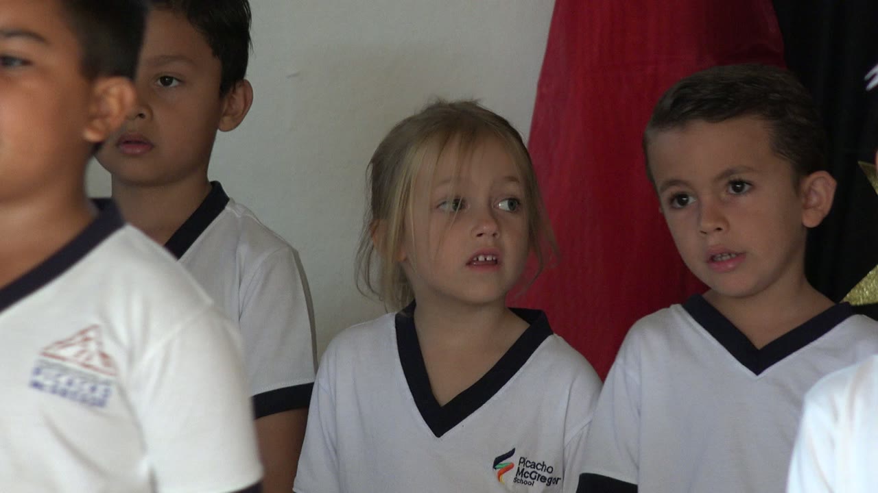 Girl in a white school uniform moving near other children.