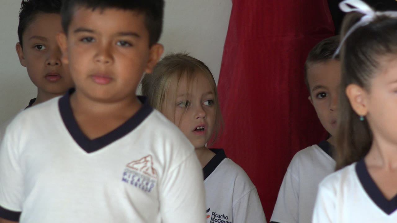 Uniformed children standing near red curtains
