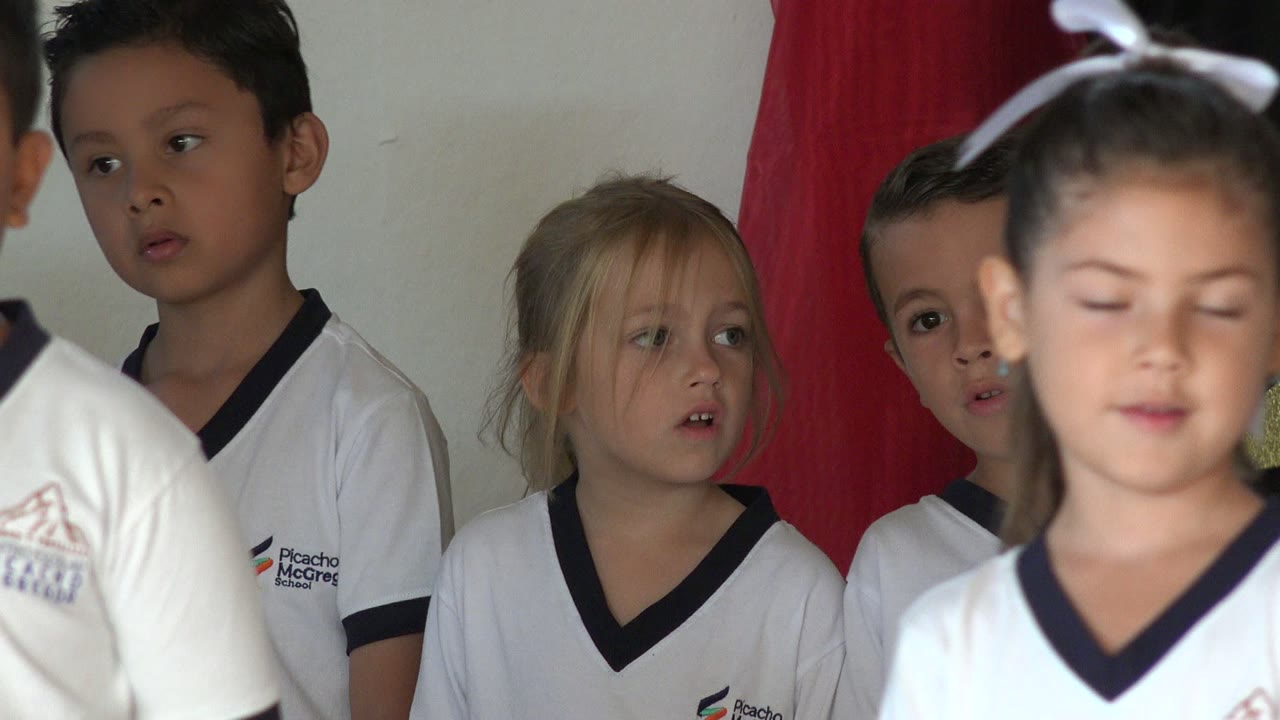 A girl with a white hair bow moves across the foreground while other uniformed children remain behind her in San Jose del Cabo, Mexico.