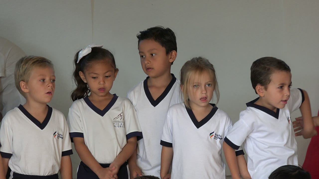Uniformed preschoolers stand close together in San Jose del Cabo, Mexico, with one child looking down and others facing across the line.