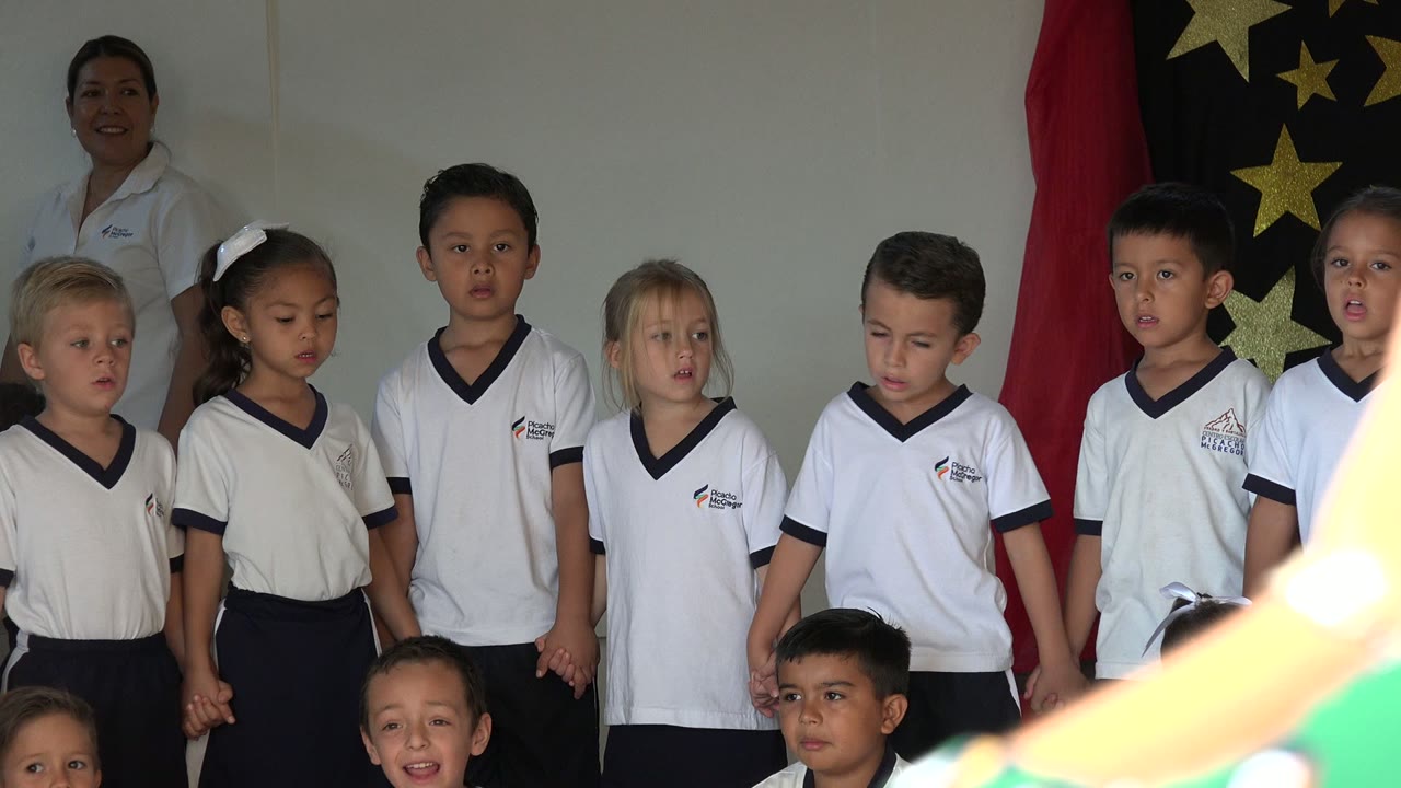 Children sing in a tight lineup with a bright foreground blur at the right.