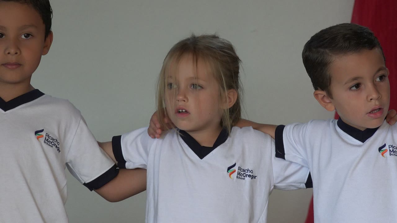 Children in white uniforms standing shoulder to shoulder.