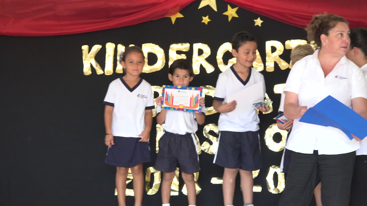 Children and an adult stand on a decorated kindergarten stage.