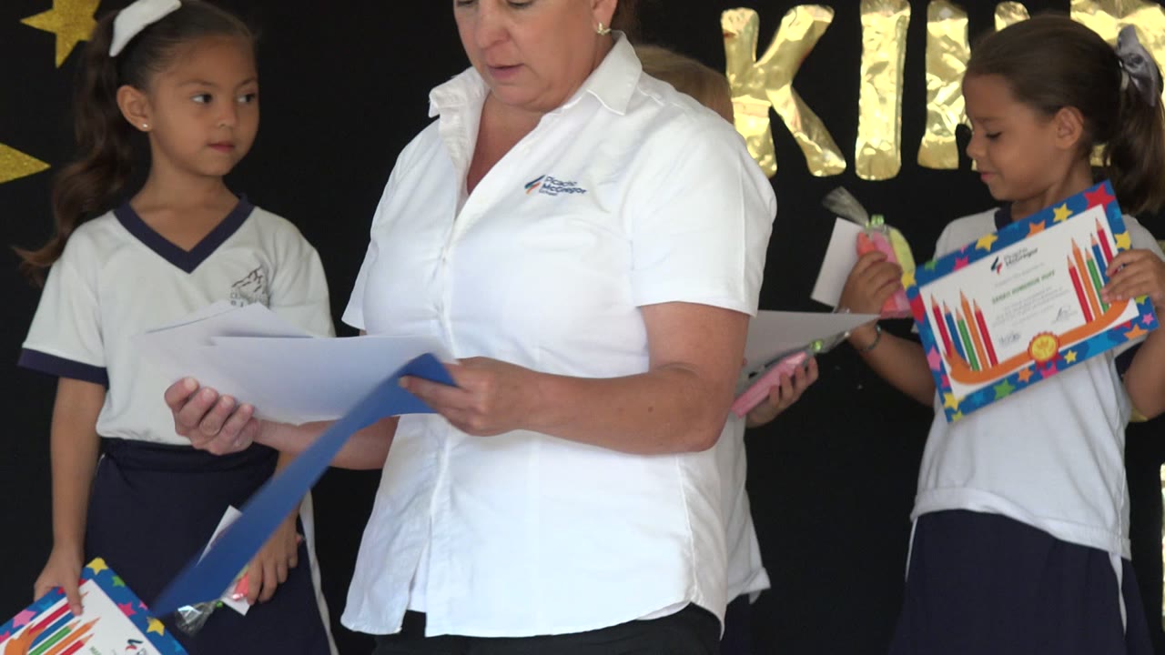 Girl in school uniform standing beside an adult holding papers.
