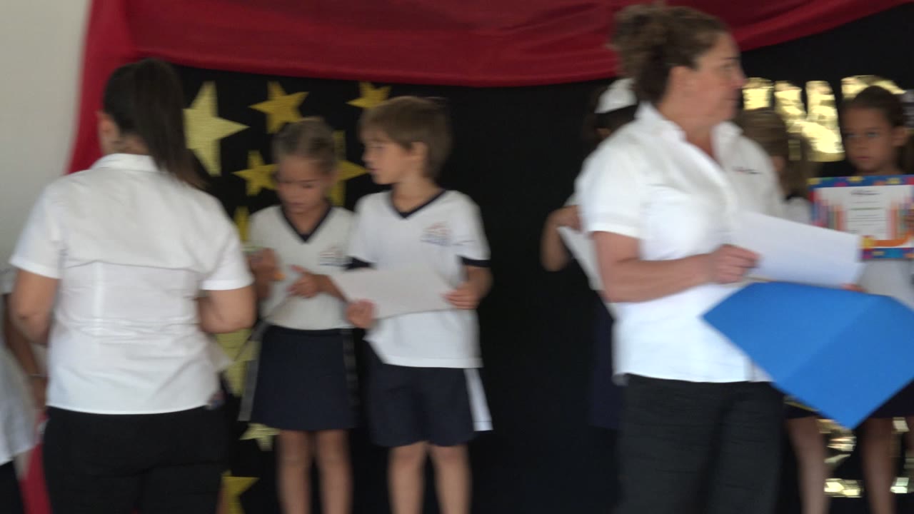 Adults and children stand near a star backdrop indoors.