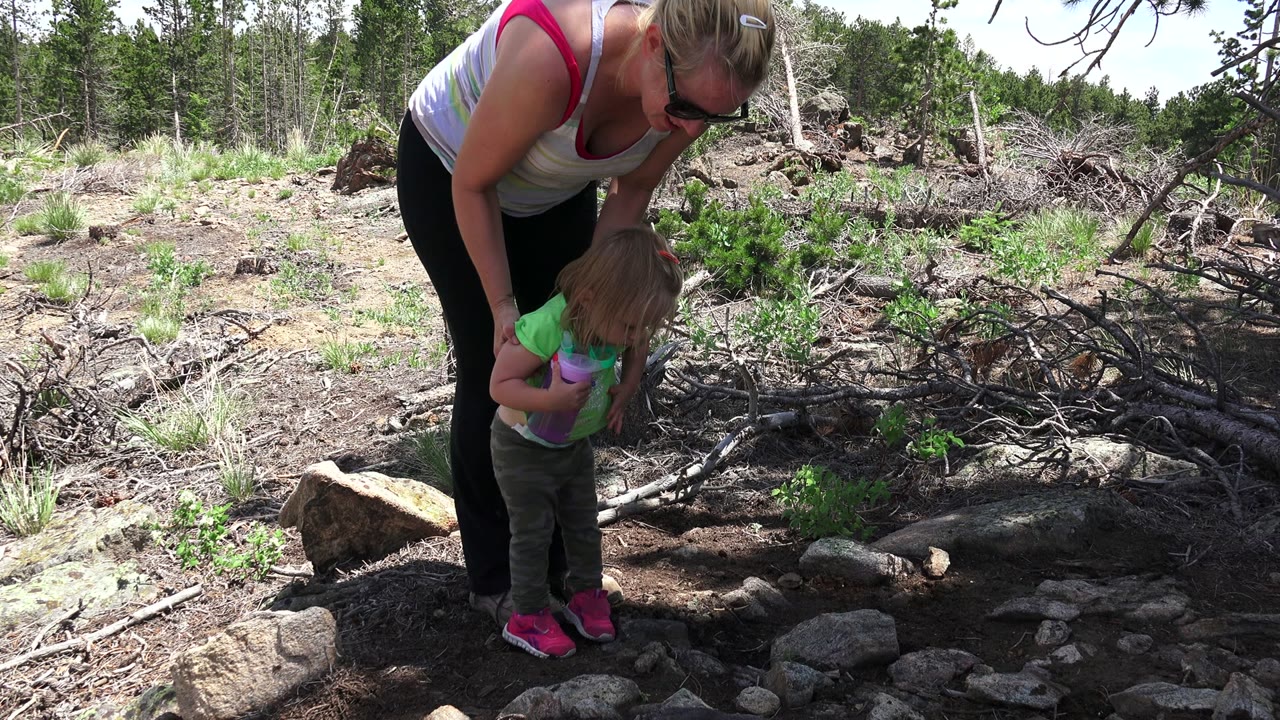 Woman bending over a small child on a rocky garden path.