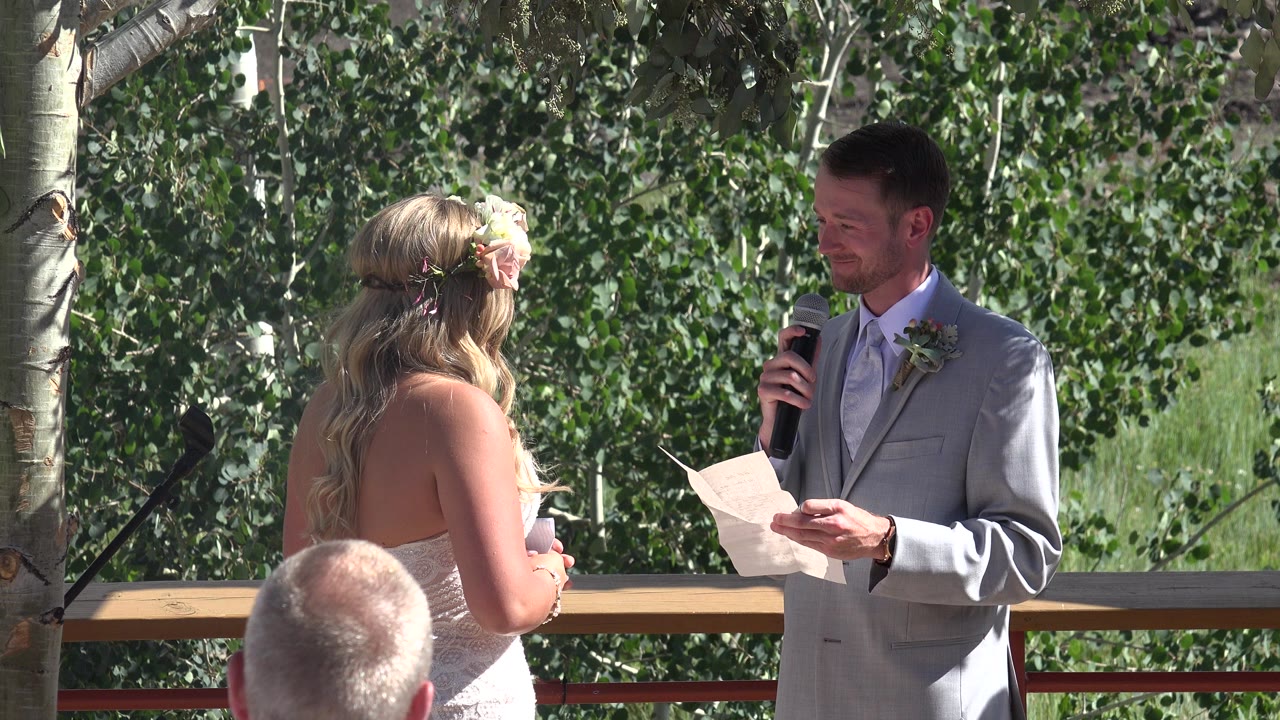 Groom reads vows to bride during an outdoor wedding ceremony.