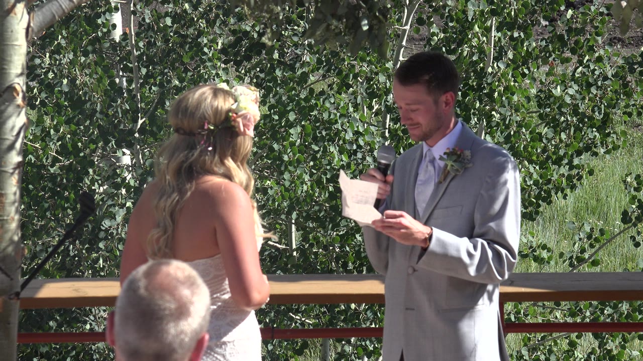 Groom reads vows to bride during an outdoor wedding ceremony.