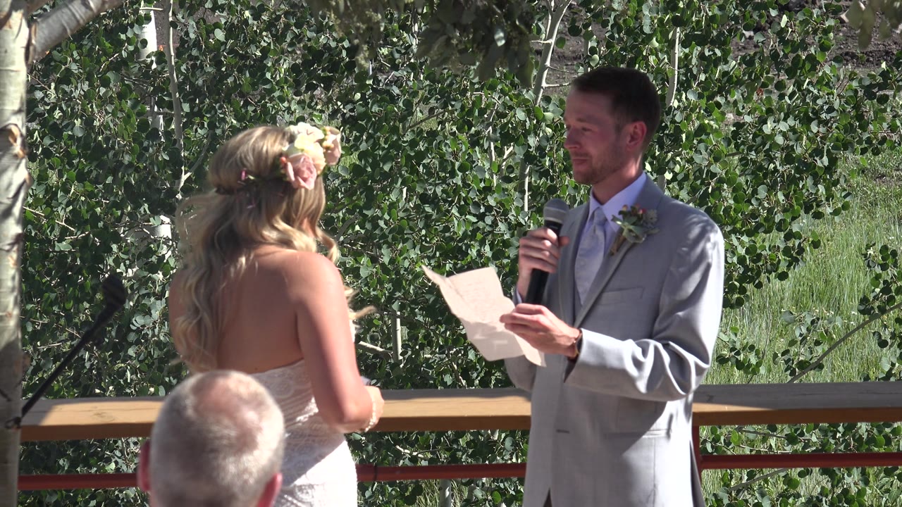 Bride and groom stand at an outdoor altar with trees behind them.