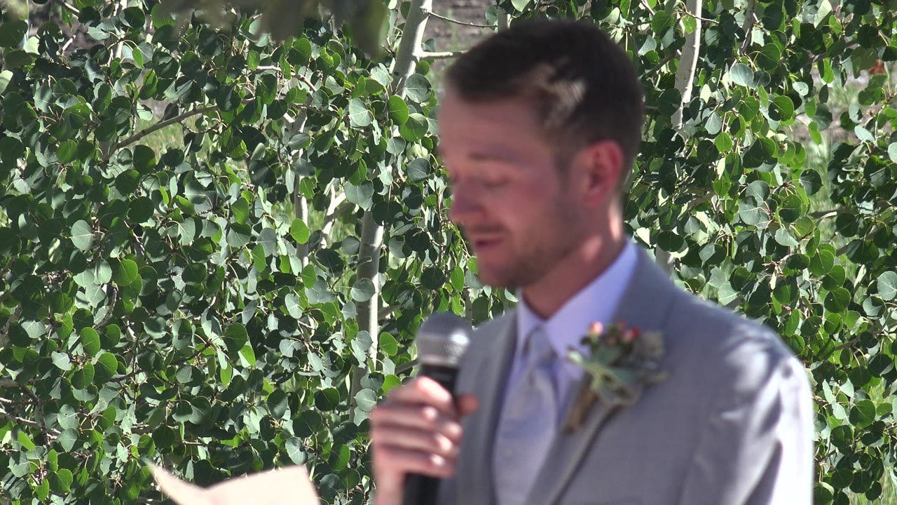 Groom holding a microphone in front of green leaves