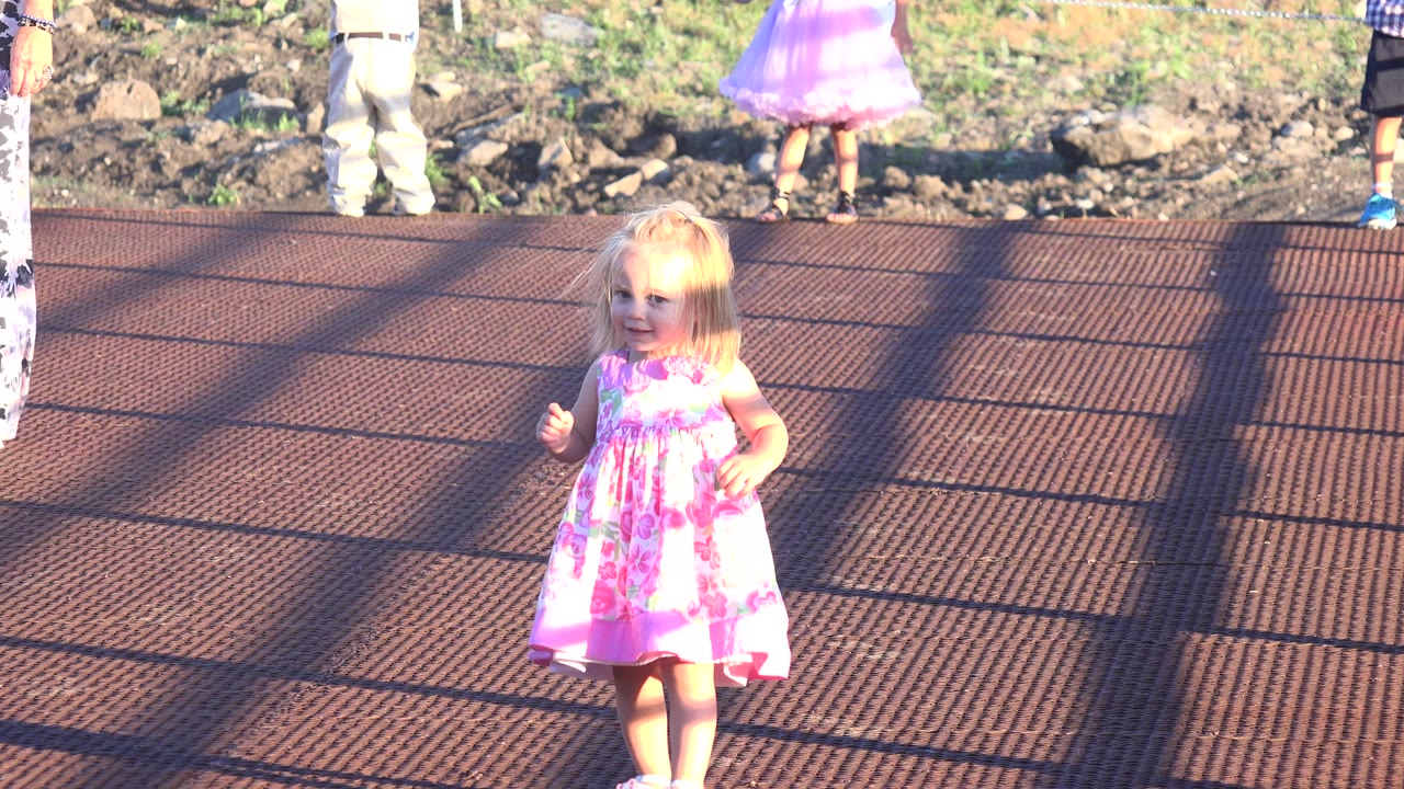 At 0:01 in Mesa, Colorado, the girl in the pink dress remains near the lower center of the frame, with the deck grid and long shadows filling most of the view.