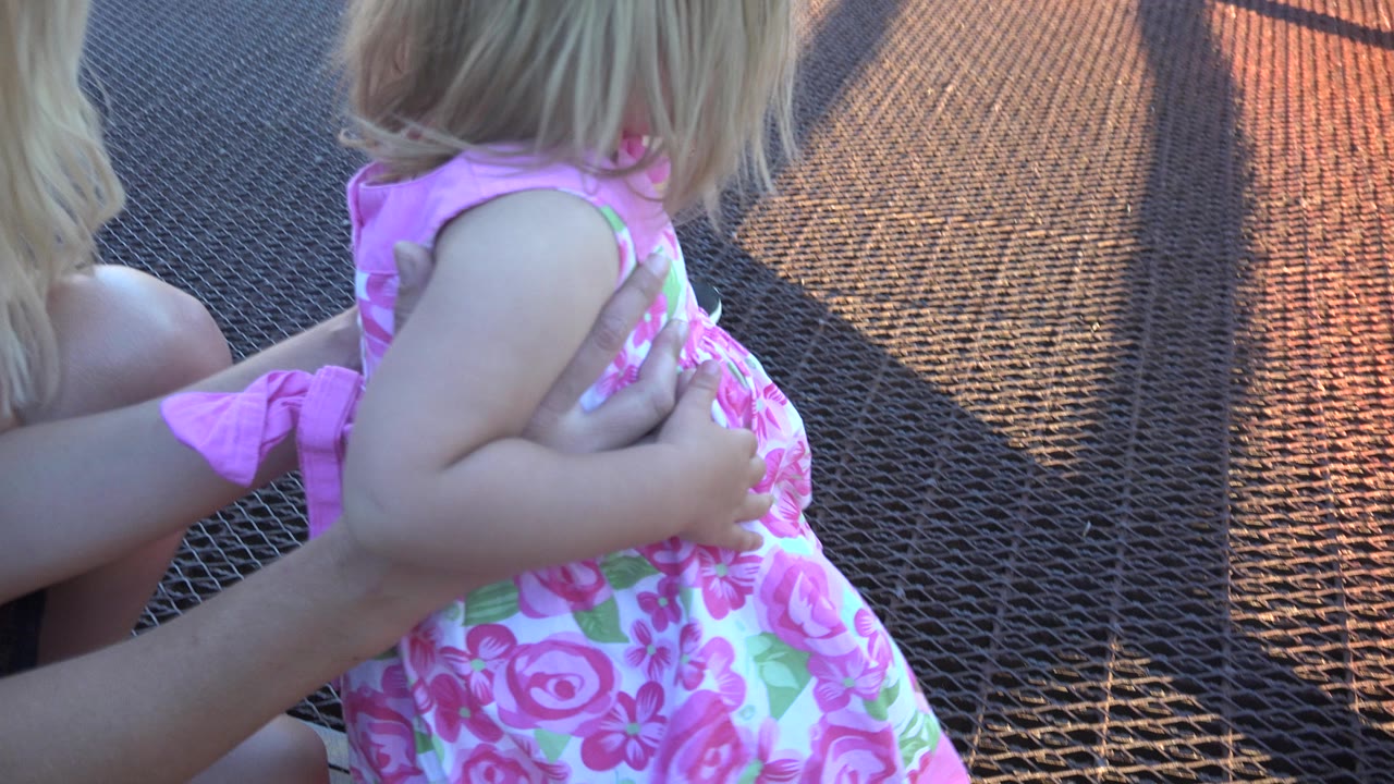 One second in, the child remains close to the camera in Mesa, Colorado, with adult hands at her side and the textured walkway filling most of the background.