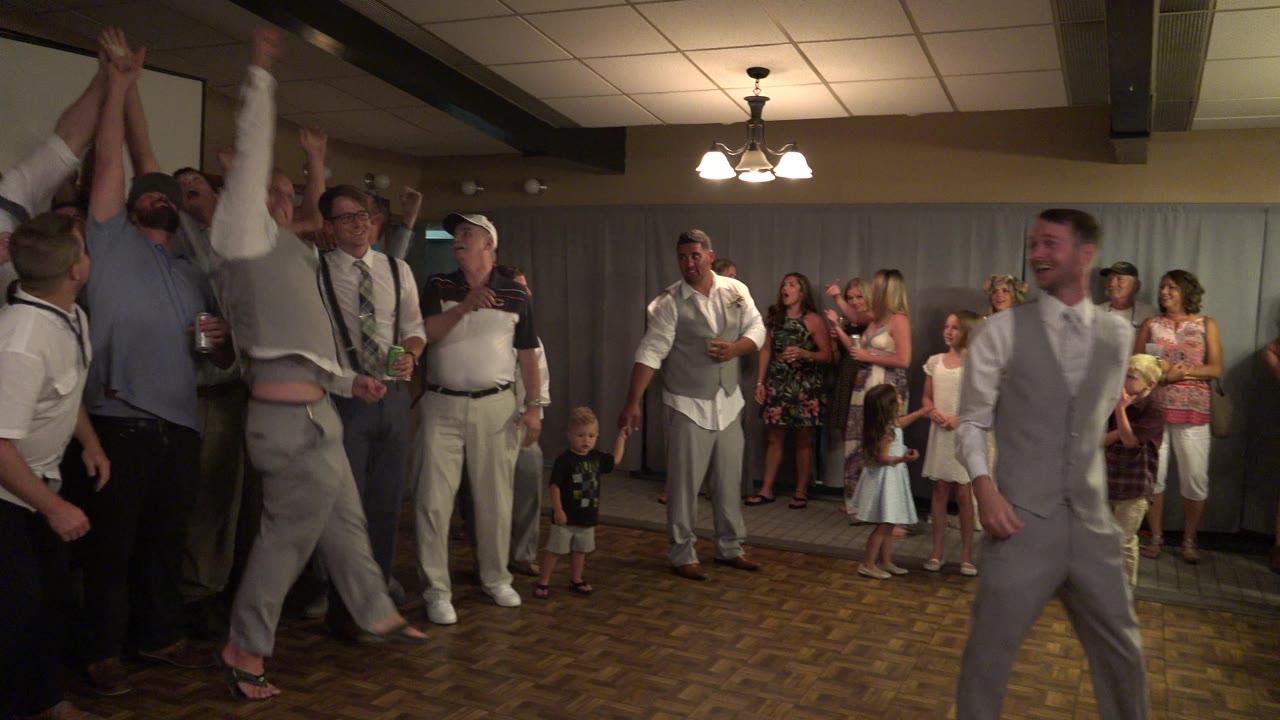 Men high-five during a wedding reception.
