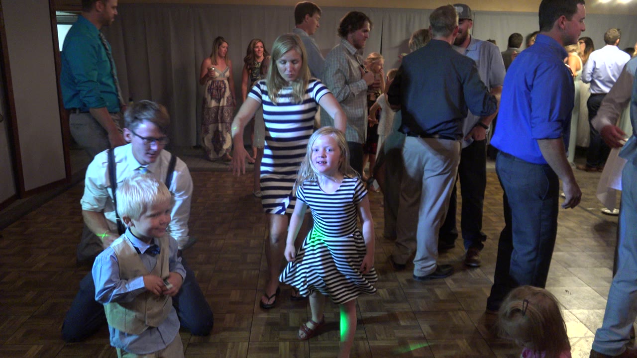 Children and adults on an indoor party dance floor with colored lights.