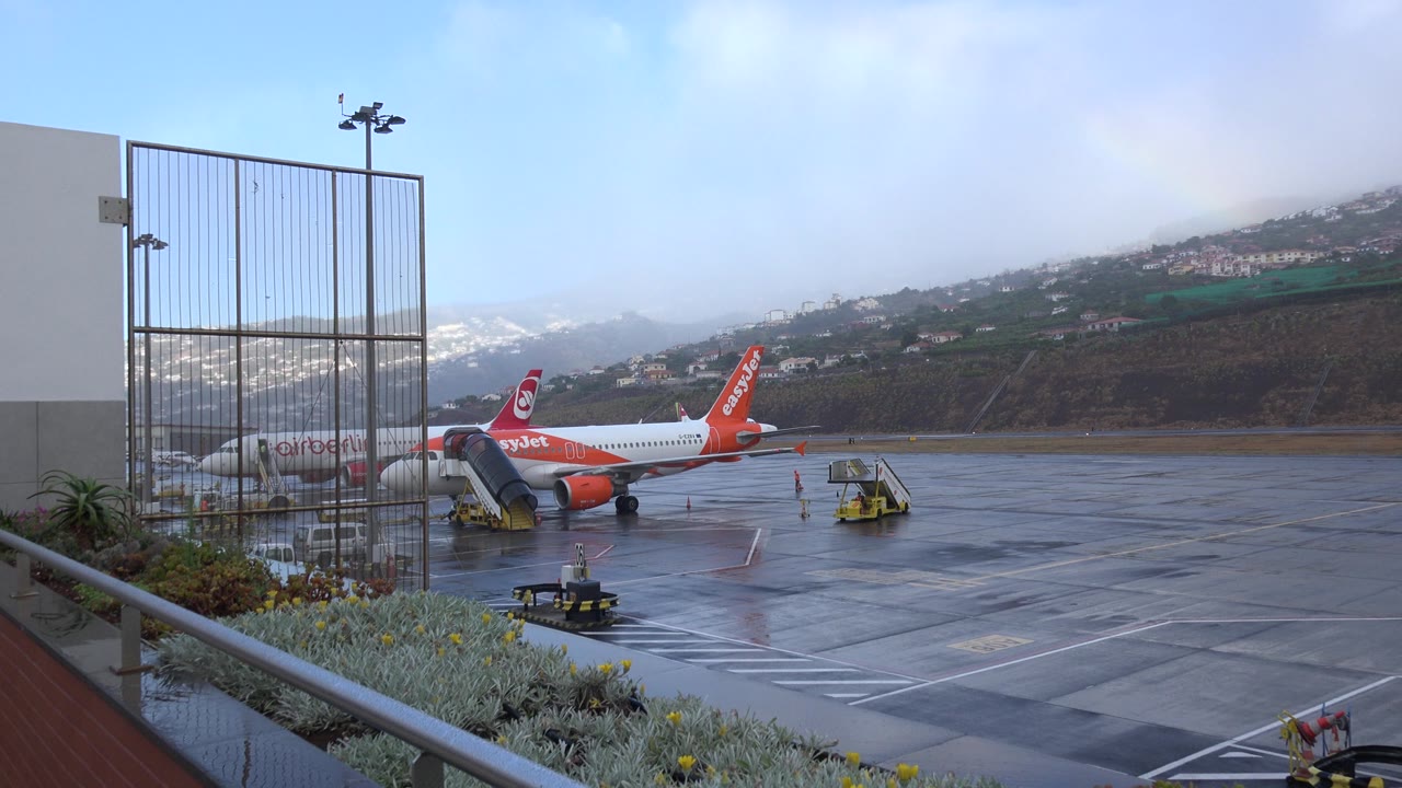 airport apron with easyJet plane, service cart, and hillside beyond runway