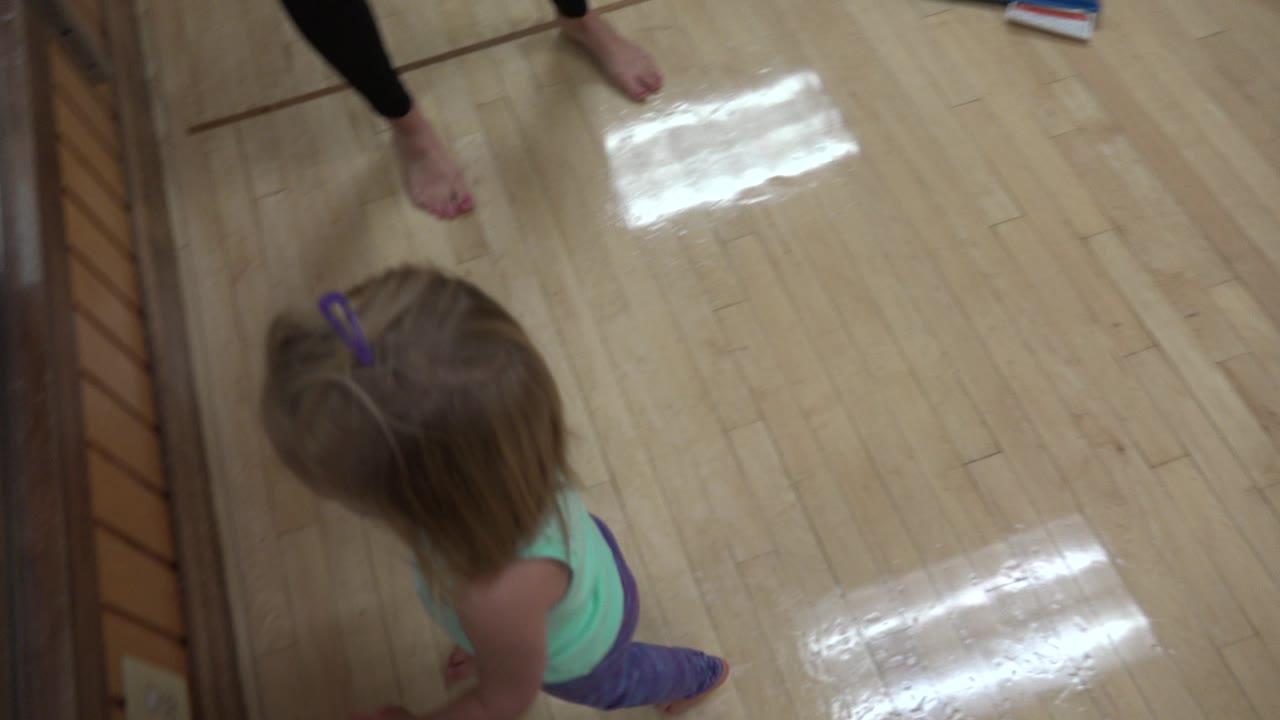 Young girl walking near a mirror and wooden barre.