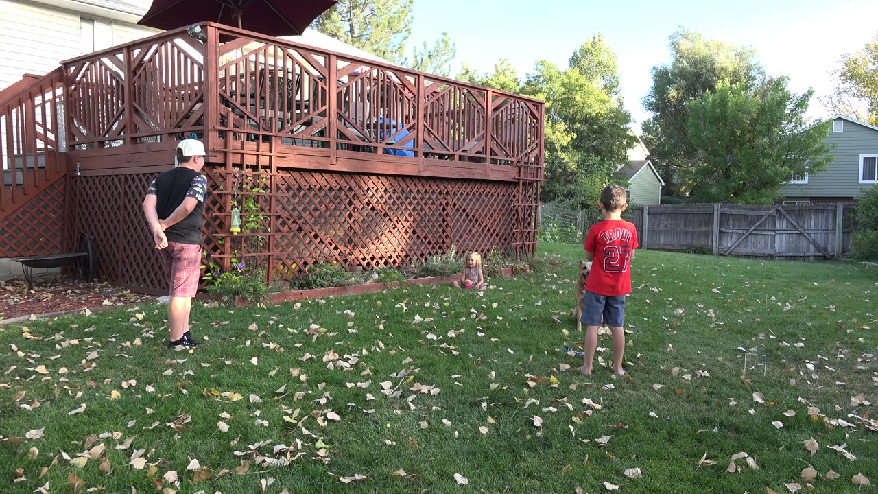 Man and boy in a backyard facing a raised wooden deck