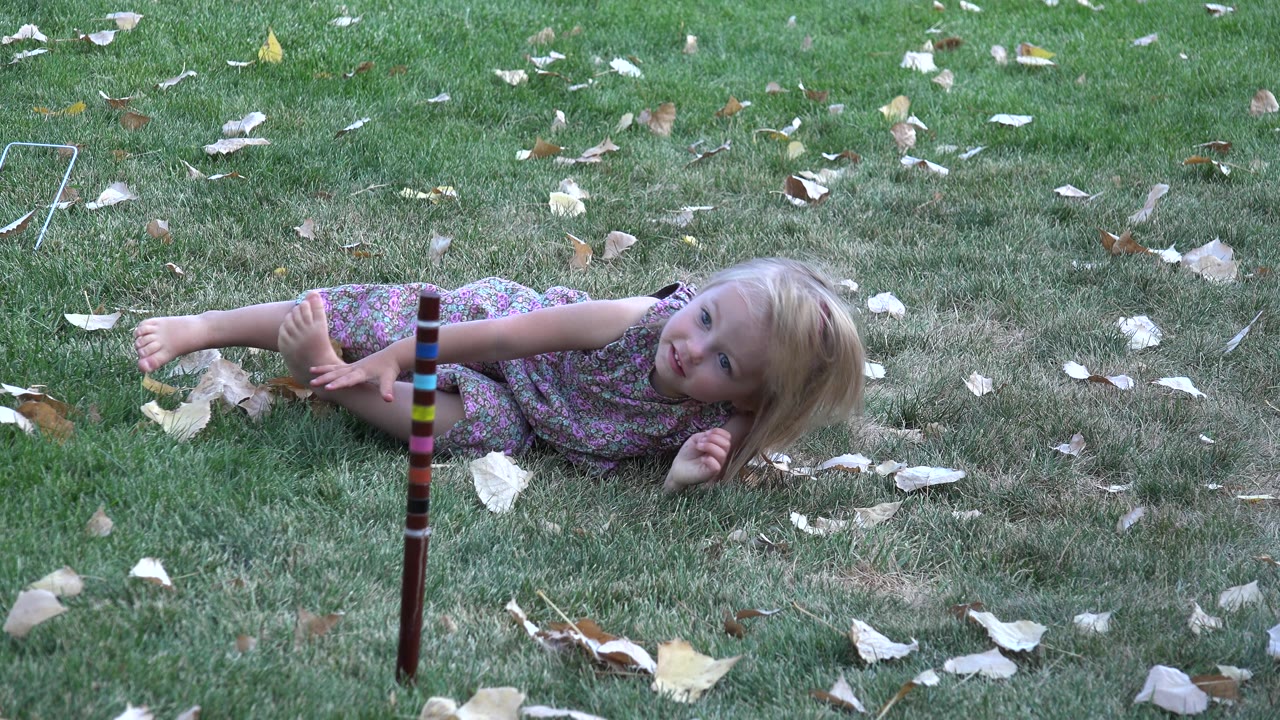 Child lying sideways on grass and looking toward camera.