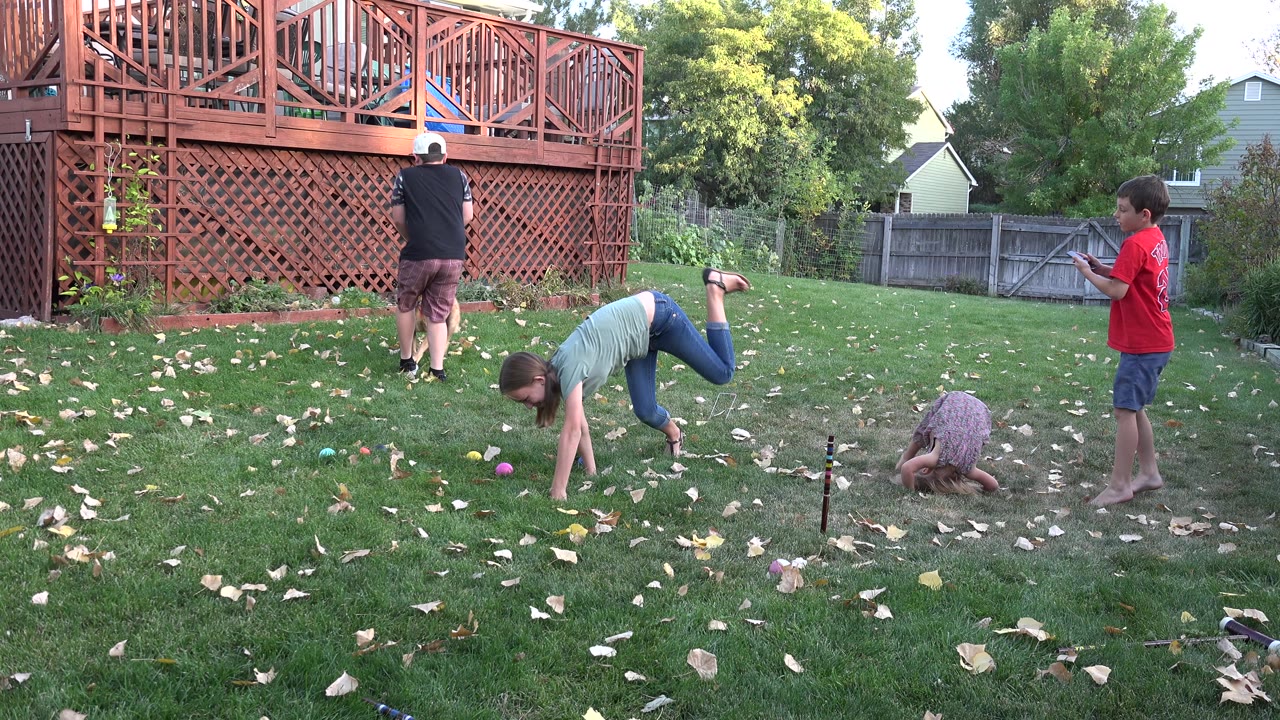 Children playing on grass near a red wooden deck