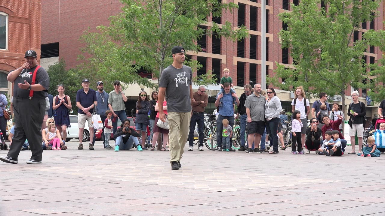 Street performer walking near a crowd in a public plaza.