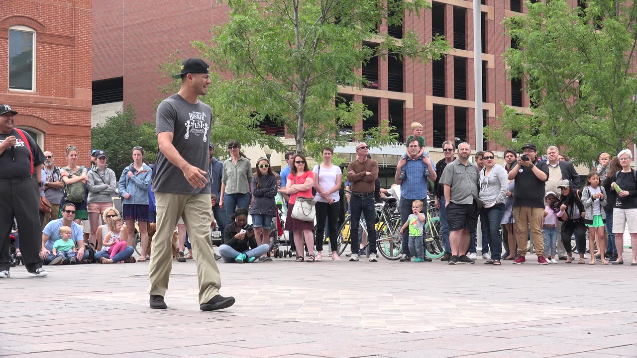 Street performer walking on a plaza in front of a crowd.