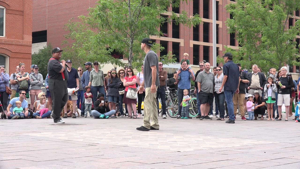 Street performers face a crowd in a paved plaza.