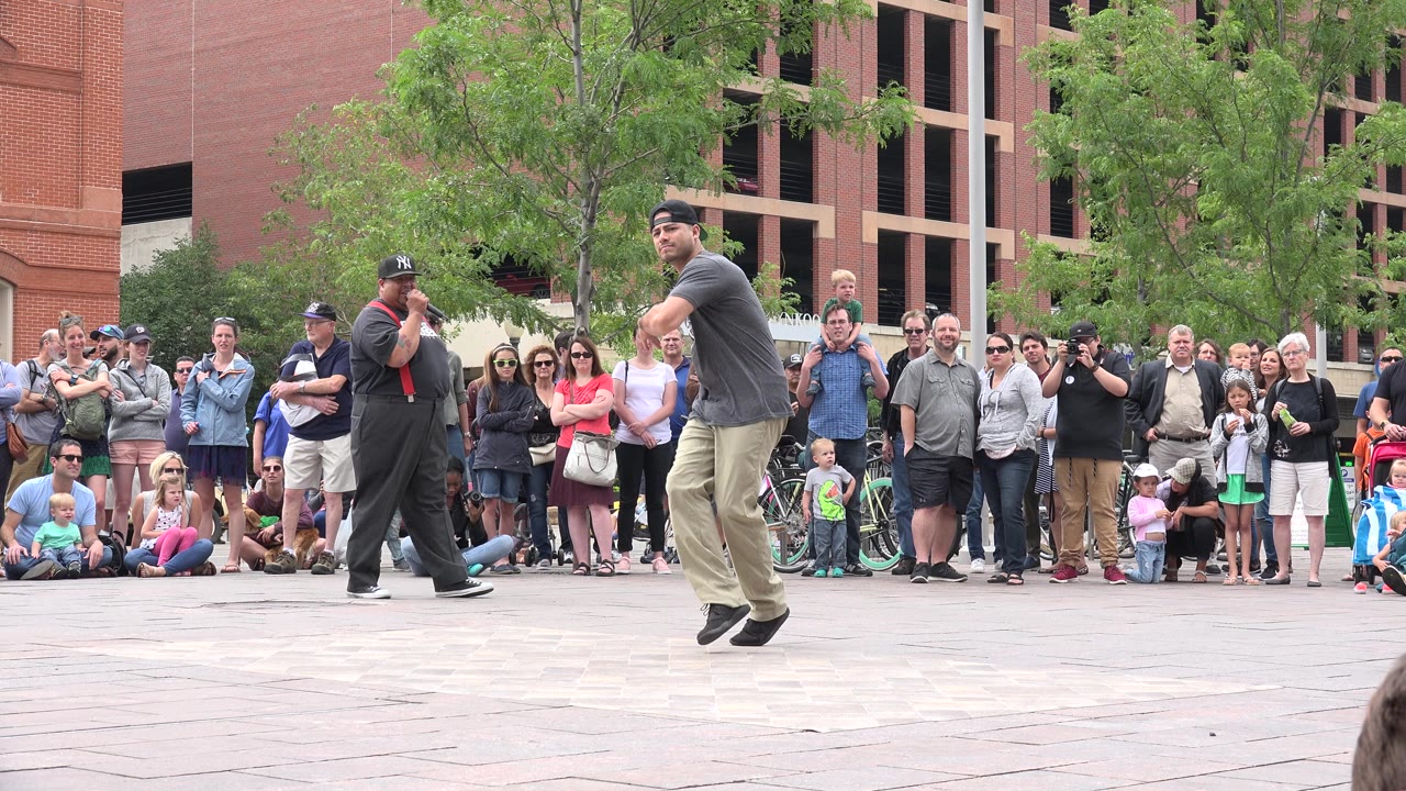 Man dancing in front of a plaza crowd.