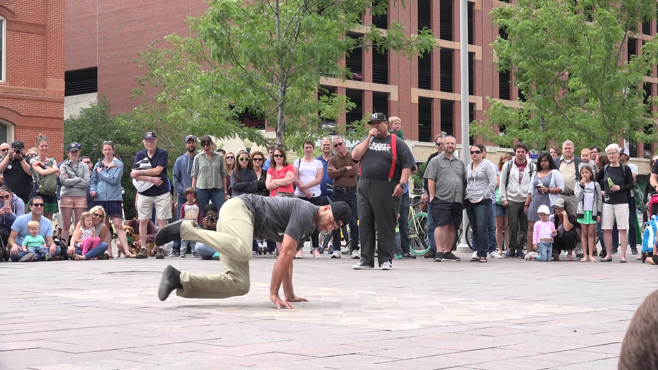 Breakdancer balancing low on one hand before a watching crowd.